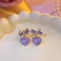 Detailed macro view of lavender purple heart earrings with elegant gold bow accents - Purple