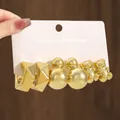 Close-up of golden geometric, spherical, and bear-shaped earring set on card - Bear Design (TZ022)