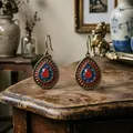 Orecchini vintage bohémien con smalto rosso e blu su scrivania in legno antico. - I Goccia Rossa