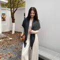 Elegant dark grey knitted triangular shawl draped over a cream top. - Dark Gray