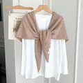 Soft brown knitted triangular shawl styled as a chic shoulder wrap over a white top. - Camel