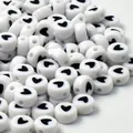 Macro detail of 7mm white acrylic beads featuring a black heart pattern for DIY jewelry making - 4mm x 7mm, 4000 Pieces / White Base Black Font