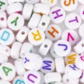 Macro detail of white acrylic 4x7mm alphabet beads with colorful letter patterns for DIY - Letter A / 100 Pieces/Pack / White Base Colored Letter