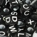 Macro detail of 6mm black square acrylic alphabet beads for DIY jewelry making and crafts - Black and White