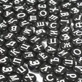Close-up detail of 7mm black acrylic beads with white Russian Cyrillic letters - 3800 Pieces/Pack / Black and White