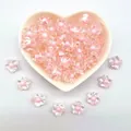 Close-up of 12mm clear acrylic flower beads with pink centers in a heart-shaped bowl - 12mm / Five-Petal Plum Blossom Style / 1000 Pieces/Pack / Pink