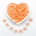 Macro shot of transparent 12mm acrylic flower beads with orange centers - 12mm / Five-Petal Plum Blossom Style / 1000 Pieces/Pack / Orange Yellow