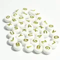 Detail shot of white acrylic beads featuring gold alphabet letters for DIY jewelry - 1600 Pieces (6x10mm) / White Base Gold Thread