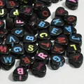 Macro detail of black heart-shaped acrylic alphabet beads for DIY jewelry design - 3800 Pieces/Pack / Black Base Colorful Letter