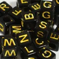 Close-up of 6mm black acrylic cube beads with gold engraved uppercase letters for DIY - Black With Gold Text