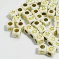 Close-up of 6mm white acrylic cube beads with gold star and moon patterns for DIY jewelry. - 3000 Pieces/Pack / White with Gold Print