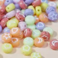 Close-up of 7mm colorful acrylic beads with star and moon patterns for DIY crafts - Colorful Base with White Letters
