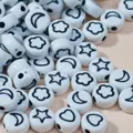 Close-up of 7mm white acrylic beads with black star and moon symbols for DIY jewelry crafts. - White Base Black Font