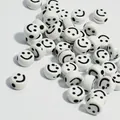 Dettaglio macro di perle rotonde in acrilico bianco con faccine sorridenti nere per gioielli - Base Bianca Linea Nera