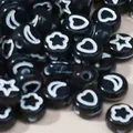 Close-up of black acrylic beads with white star and heart shapes. - Black and White