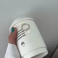 Nahaufnahme eines elastischen Silberperlenrings mit weißem Blumenanhänger auf Becher - Fünfblättrige Blume-Stil (J4357)