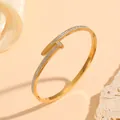 Detailed macro view of a golden stainless steel nail bangle paved with sparkling crystals. - Nail Shape Rhinestone Style (S408) / Gold