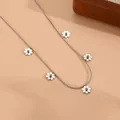 Macro view of dainty silver daisy flower charms on a stainless steel snake chain - Steel Color Daisy Necklace