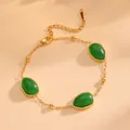 Gros plan d'un bracelet en acier doré avec des pierres vertes ovales et perles. - Bracelet Vert (A619) / Or