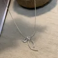 Detaillierte Nahaufnahme eines silbernen Schleifen-Anhängers an einer feinen Schlangenkette. - Eleganter Schleifenstil (XL3063)
