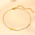 Detail view of a gold-plated titanium steel cross bracelet with a small crystal - Anklet (Q103) / Gold