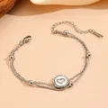 Makrodetail eines zweilagigen silbernen Edelstahlarmbands mit einem Herzanhänger-Motiv - Stahlfarbe Doppellagiges Herz Armband