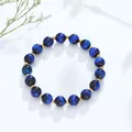 Blauwe kyaniet-stijl kralenarmband met gouden tussenstukken op een schone witte achtergrond. - Lapis Tijgeroog Gouden Stijl