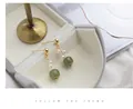Gros plan d'élégantes boucles d'oreilles en or avec perles blanches et jade vert. - Boucles d'Oreilles Clous en Jade