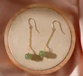 Gros plan d'élégantes boucles d'oreilles en chaîne dorée avec perles de jade. - Boucles d'Oreilles Crochet en Jade