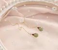 Détail d'élégantes boucles d'oreilles dorées avec perles de jade vert et pierres rouges. - Boucles d'Oreilles Traversantes Jade Grenat