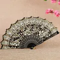 Elegante abanico chino plegable con intrincados motivos florales de encaje negro y toques dorados - Negro