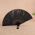 Black Chinese folding fan with hollow bamboo ribs, willow pattern, and elegant tassel. - Style 2