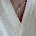 Minimalistische 925er Sterlingsilber Schleifen-Halskette an einem Modell in Weiß. - Süßer Schleifenstil (XL2285)