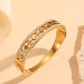 Detail shot of a stainless steel gold cuff bracelet with flower patterns and rhinestones. - 金色花朵镶钻款(H416)
