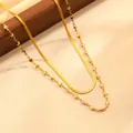 Détail de collier doré double couche, avec chaîne serpent élégante et pendentifs étoiles et cœurs. - Collier double rang étoile et cœur dorés avec maille plate