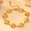 Detail of gold titanium steel bracelet with shell charms on a textured background - Shell Bracelet H806