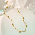 Close-up of a gold titanium steel necklace with small heart charms on a white riser - 项链B109 / Gold