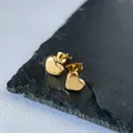 Close-up of minimalist gold heart stud earrings made of stainless steel on dark stone. - 耳钉G305 / Gold