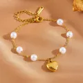 Detailed macro view of a gold-tone stainless steel heart and pearl bracelet on silk fabric. - #1 Heart