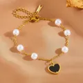 Gedetailleerde macrofoto van een gouden roestvrijstalen armband met parels en een hartje - Zwarte Schelp Hydraulisch Hart