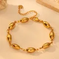 Detailed macro view of golden stainless steel bracelet with glossy hollow oval beads - Oval Bracelet H812