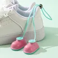 Mini pink boot-shaped shoe deodorizer ball hanging on white sneakers for freshness. - Pink