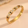 Gedetailleerd macrozicht op een 18k vergulde titanium stalen armband met inleg - Gouden schakelarmband met zwarte schelp en strass F718