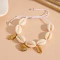 Close-up of handmade natural cowrie shell bracelet with gold-tone ocean charms on beige background - Shell Beaded Bracelet / White