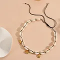 Detailed close-up of natural cowrie shell necklace with golden sea animal charms - Small Fish Necklace / Black