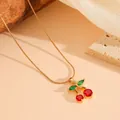 Gedetailleerde weergave van rode kersenhanger met groene kristallen op gouden slangenketting - Kersen Ketting / Goud