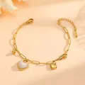 Detailopname van de gouden hartjeshangers aan een roestvrijstalen schakelarmband. - Hart Kraal Stijl (E415) / Goud