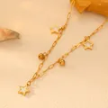 Close-up of gold stainless steel necklace featuring star charms and beads on textured background. - White Shell Star Necklace