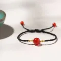 Handmade black braided string bracelet with a central red agate bead - Braided Cord Gold Tied (Single Bead) Bracelet / Single Bracelet