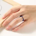 Detailed view of 2mm blue faceted beaded ring with small golden luck coin charm on hand - Lapis Lazuli